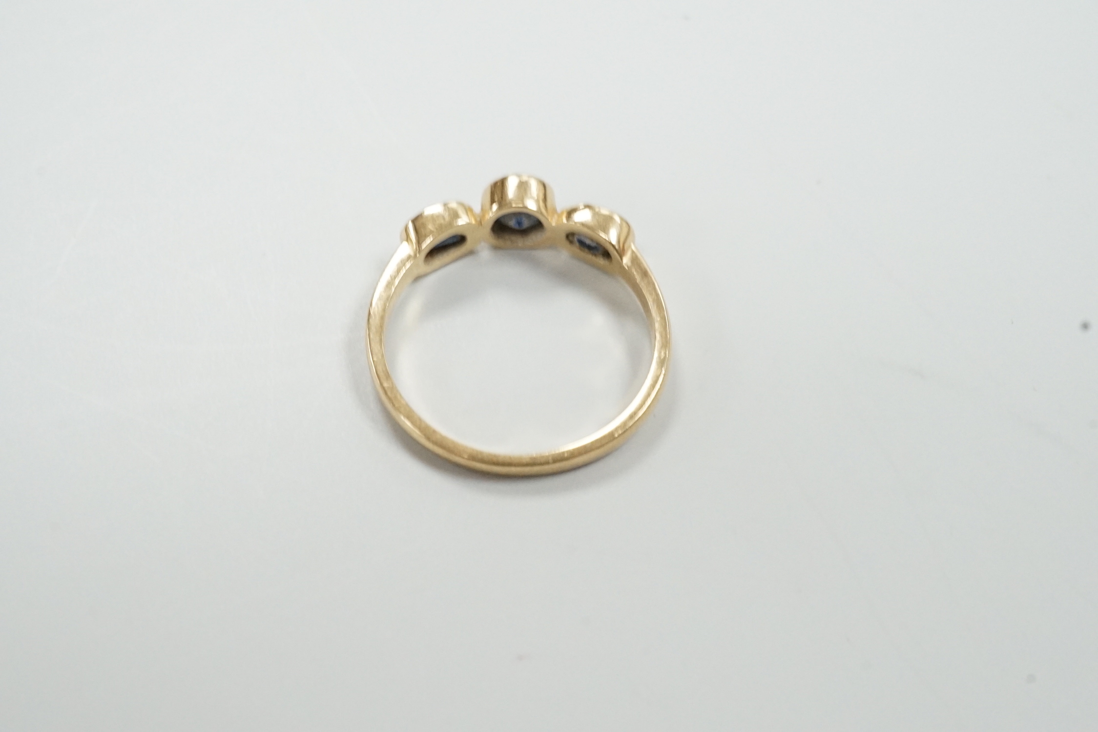 A modern 585 yellow metal and three stone sapphire set ring, size O, gross weight 2.4 grams.